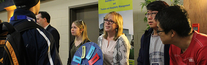 Business and Tourism instructors and students giving information at a open campus day event