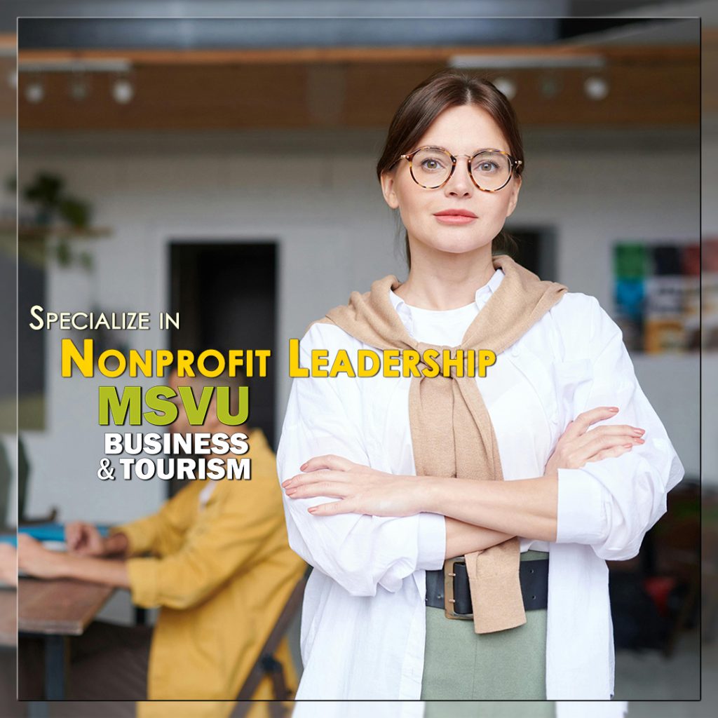 This is a photo of a white woman in the foreground wearing a white shirt with a beige sweater tied over her shoulders. She has brown circular glasses and brown hair tied back. In the background are three people working in an office. The words specialize in Nonprofit Leadership with the MSVU business and tourism logo are placed in the middle of the photo.
