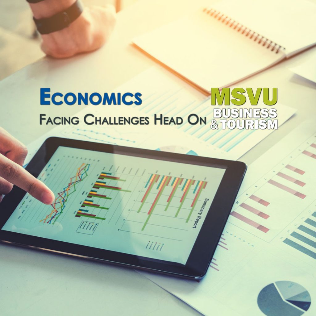 This is a photo of a tablet on a table with three different kinds of graphs on it. A person is leaning on the table and pointing at the last graph. Under the tablet are papers with more graphs and line charts. The words Economics facing challenges head on with the MSVU business and tourism logo is centered in the photo above the tablet.