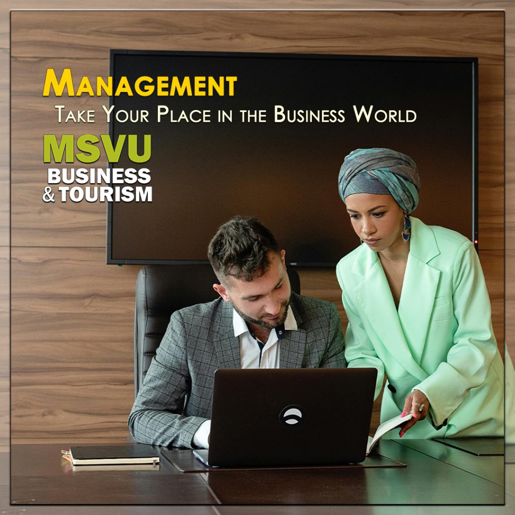 This is a photo of two people in a brown office looking at laptop that is on a desk. A woman with a head scarf wearing a light green blazer is standing showing a man with dark hair and a grey blazer something on a computer. The word Management is centered in yellow above the words in white, take your place in the business world which is above the MSVU business and tourism logo.