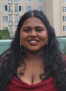 Headshot of Afeefa Mohamed. Afeefa is a brown woman with long brown wavy hair and a big beautiful smile. 