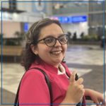 Photo of Brenda MacDonald-Lona. Brenda has short brown hair and glasses. She has a pink shirt and is smiling at the camera.