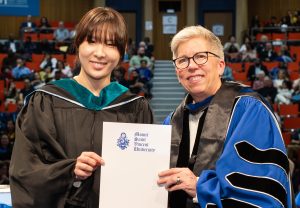 Tourism and Hospitality Management student on stage with president at the May 2026 graduation ceremony. Both look very happy.