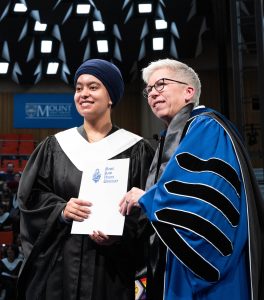 Tourism and Hospitality Management student on stage with president at the May 2026 graduation ceremony. Both look very happy.