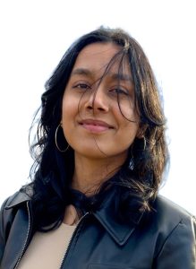 Headshot of Reet who is the recipient of the 2026 Accounting Achievement Award. Reet is a smiling woman who has dark wavey hair, is wearing a black leather zip up jacket and a white shirt.  She is standing in front of a while background.