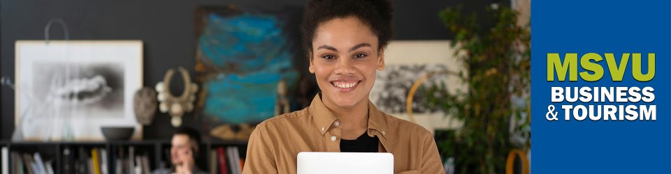 This is a photo of a smiling black woman holding a laptop wearing a brown button up shirt in the foreground with a white man in the background on the phone sitting in front of a desk in a trendy office. On the right with a blue background is the MSVU business and tourism logo.