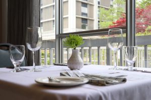 Table set near window with white table cloth, centre piece is an ornamental plant in the Mount's Tourism and Hospitality Management student restaurant called Vincent's.