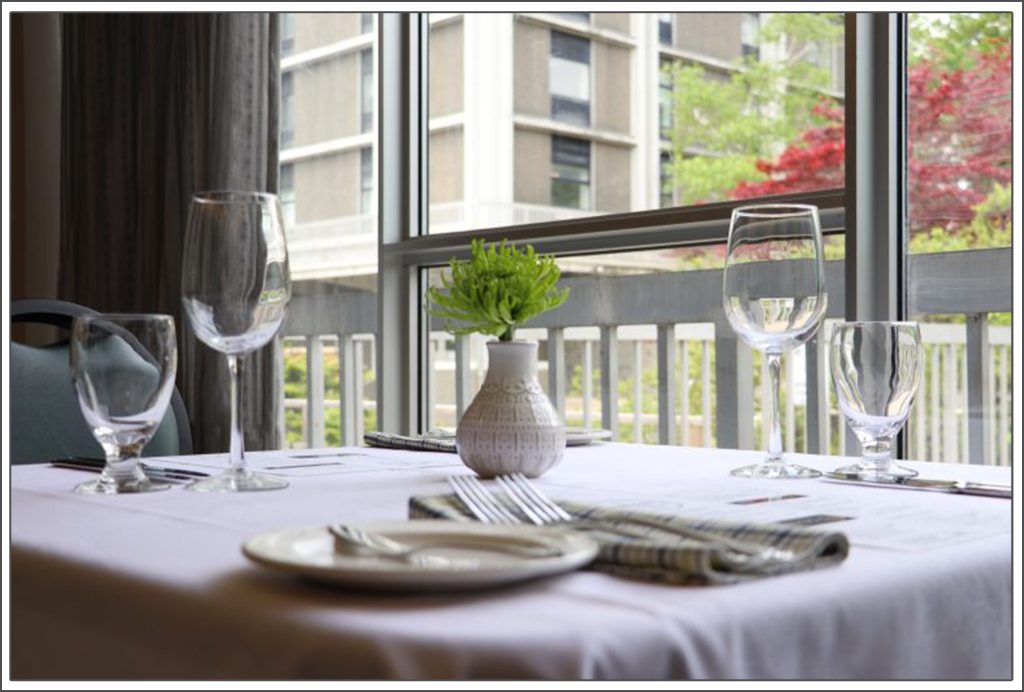 Table set near window with white table cloth, centre piece is an ornamental plant in the Mount's Tourism and Hospitality Management student restaurant called Vincent's.
