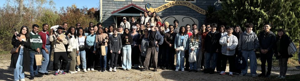 Mount Saint Vincent University Business and Tourism department students from the fall 2025 sustainable business tour standing in a line outside of the Lunenburg County Winery half way through the tour.