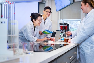 Three students working in a food lab on campus