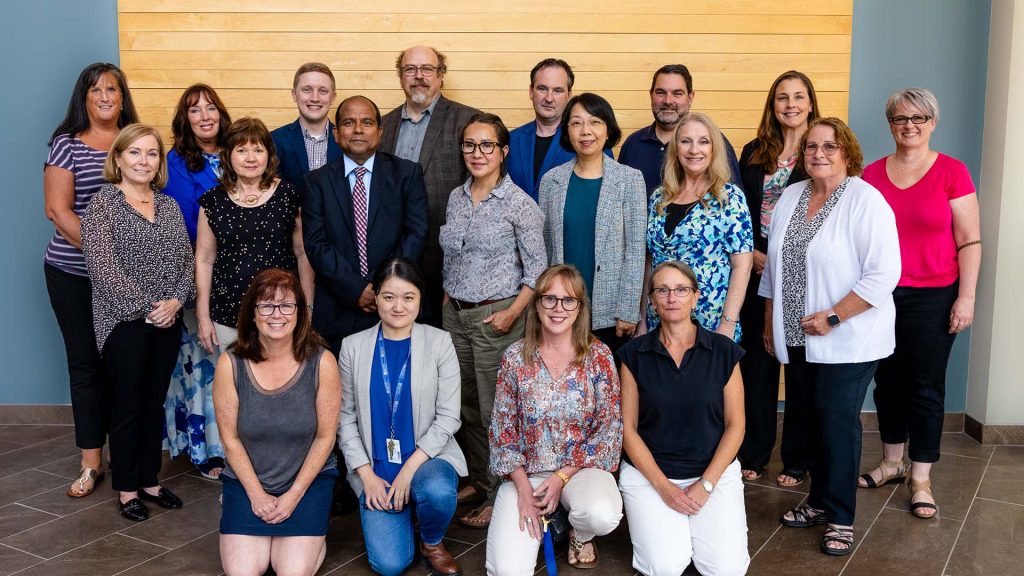 Some business and tourism faculty and staff standing for a group photo in the McCain atrium.