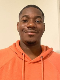 Philip, a Black man with short-cropped hair wearing an orange hoodie and smiling at the camera.