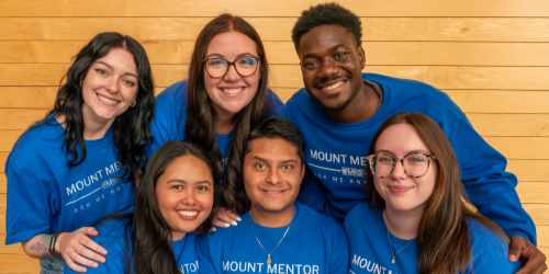 6 Mount Mentors in blue shirts smile at the camera.
