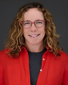 Isabelle Nault, Vwearing a red blazer and black shirt, smiling at the camera