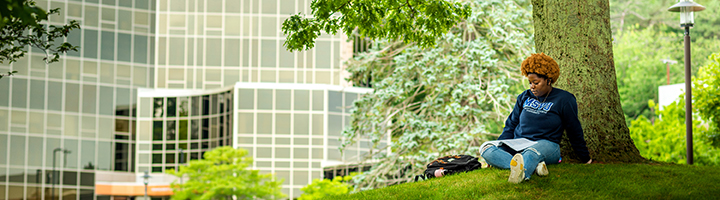 Student sitting under a tree, reading a book