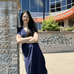 Dr. Jessie-Lee McIsaac leaned up against a stone wall smiling at the camera.