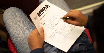 Business and Tourism student sitting in auditorium during the 2020 SE4D event holding a pen and worksheet