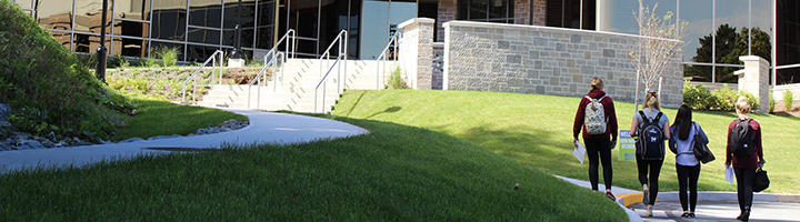 Four students walking up to the McCain building