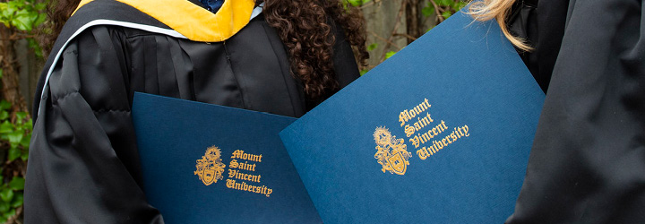 MSVU Graduates holding their degrees outside of Seton Academic Centre