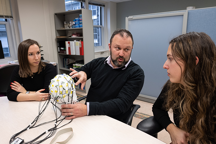 Derek Fisher holding brain scan model in EEG lab