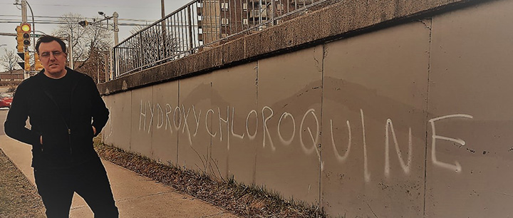 Dr Joanthan Roberts standing near a barrier that says "hydroxychloroquine"