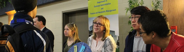 Business and Tourism instructors and students giving information at a open campus day event