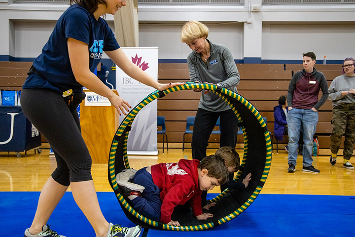 President Bluechardt helping two PACE participants with one of the new pieces of equipment