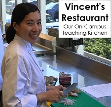 Tourism and Hospitality Management student in the kitchen at Vincent's restaurant cutting up vegetables and smiling for the camera