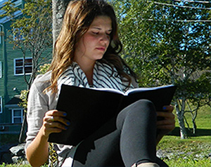 Student reading with a book outside near the Birches Residence