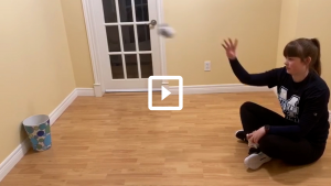 Woman playing a game of sock basketball throwing a sock into a bin