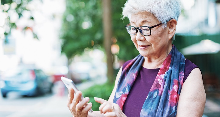 Senior woman in the city using phone to call taxi