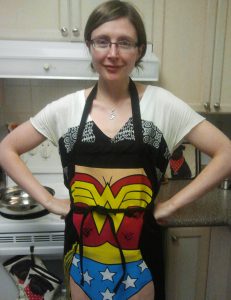 Shannan Grant wearing wonder woman apron standing in front of stove