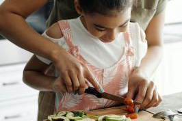 Child and adult cutting vegetables