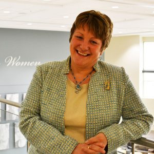 Janice Keefe standing in front of the Women's Wall of Honour