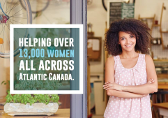 A women standing beside a sign that reads "Helping over 13,000 women across Atlantic Canada"