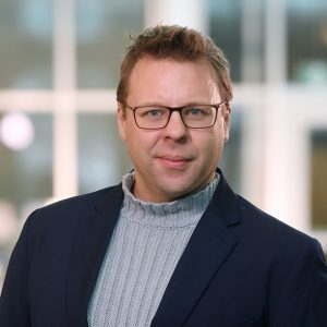 Dr. Phillip Joy wearing navy suit jacket and gray turtleneck sweater