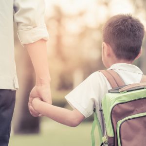 A Parent and child holding hands preparing for the first day of school