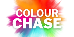 The image shows the words 'COLOUR CHASE' in bold white capital letters, centered on a vibrant background of splattered colors including red, orange, yellow, green, blue, and purple.