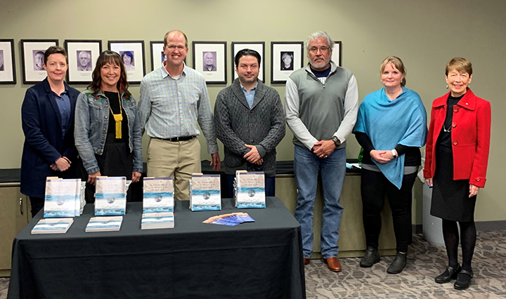 Group of people posing for photo in front of table full of books