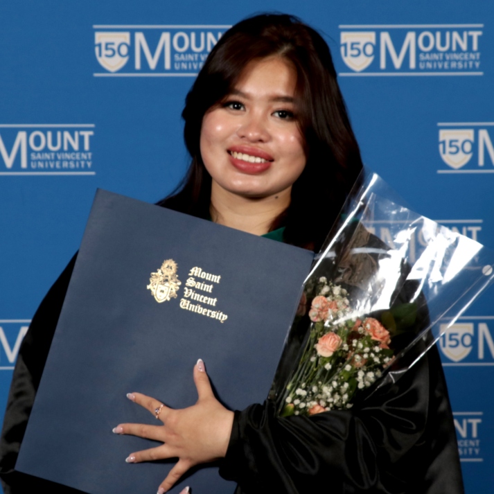Photo of tourism student, Thuy Bao Tran Pham in graduation gown holding diploma and flower bouqet