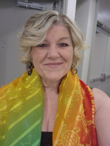 Lori Paul, wearing a rainbow-coloured shawl, smiling at the camera