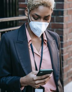 Business woman wearing face mask and looking at smart phone