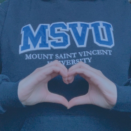 A MSVU hoodie with the hand making the shape of a heart