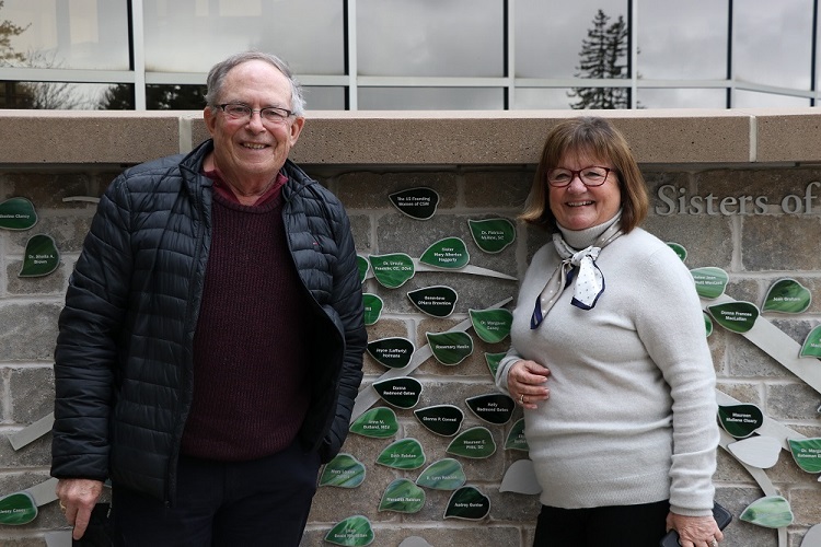 Two people standing beside one of the leaves at the Women's Wall of honour