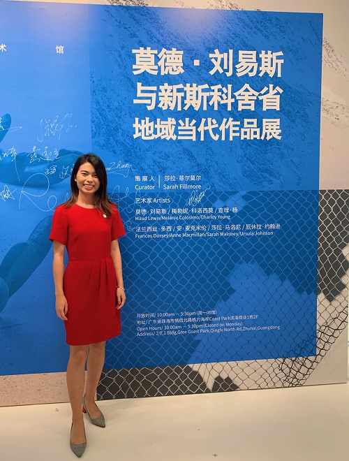 Christine Yang standing beside the Maud Lewis Exhibition in China