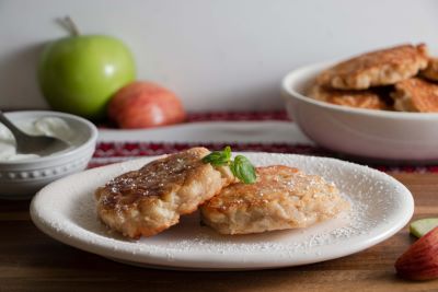 Two Ukrainian apple pancakes on a plate with powdered sugar