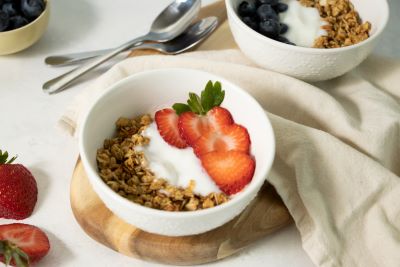 Yogurt, granola, and sliced strawberries in a white bowl