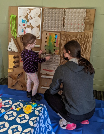 A Child showing off some arts and crafts to a CHYS 3314 course student