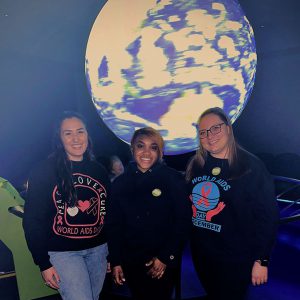 Three people standing in front of a large globe
