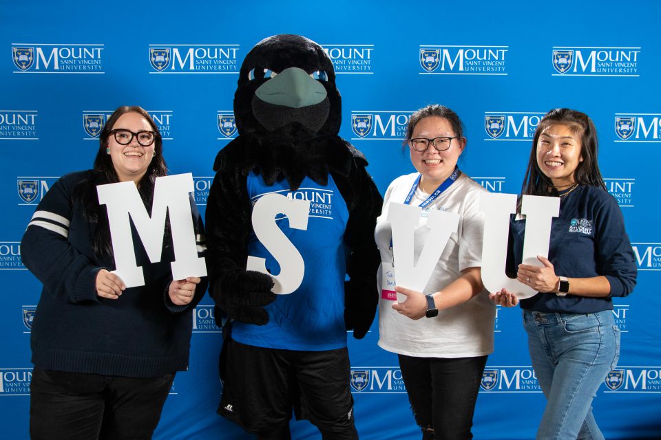 Group of people standing with Captain Crow holding letters M-S-V-U